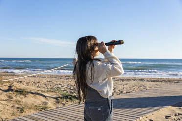 Mädchen beobachtet das Meer durch ein Monokular an einem sonnigen Tag - MEGF00114