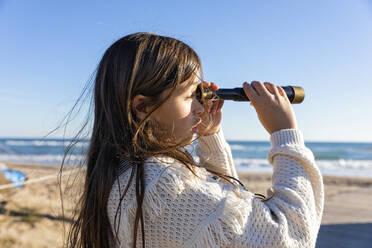 Girl looking through monocular at beach - MEGF00115