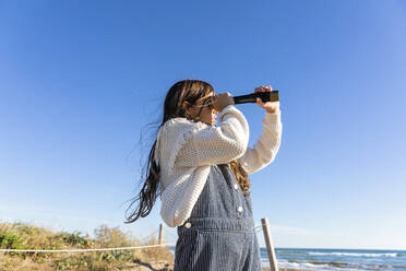 Girl watching through monocular at beach - MEGF00116