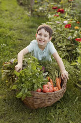 Glücklicher Junge mit Gemüsekorb im Garten - ONAF00045