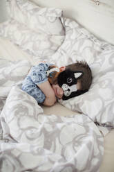 Smiling boy wearing sleep mask on bed - ONAF00066