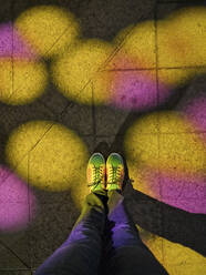 Bunte Lichter, die auf die Schuhe eines Mannes auf dem Gehweg fallen - JSMF02411