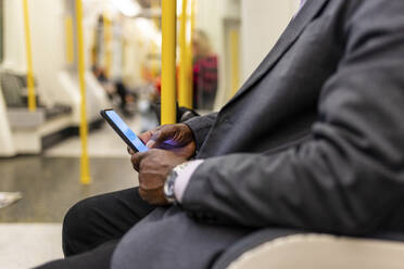 Senior commuter using mobile phone in subway train - WPEF06416