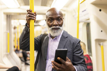 Senior passenger with smart phone in subway train - WPEF06419