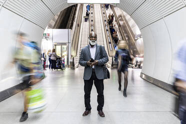 Älterer Pendler mit Mobiltelefon im Bahnhofstunnel - WPEF06441