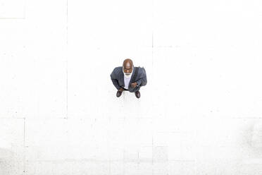 Senior businessman standing on white flooring at railroad station - WPEF06462