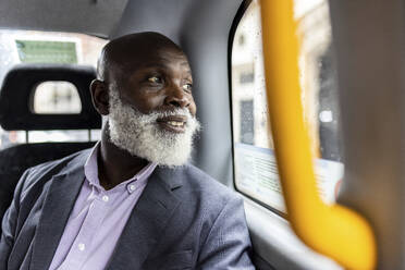 Lächelnder älterer Pendler, der durch das Taxifenster schaut - WPEF06482
