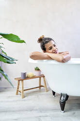 Thoughtful smiling woman in bathtub - VEGF05969