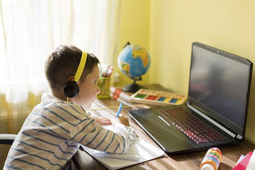 Boy wearing headphones using laptop at home - ONAF00089