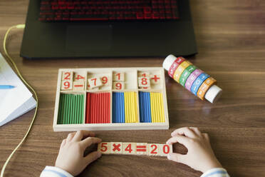 Hand's of boy arranging number blocks at home - ONAF00091