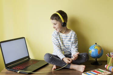 Smiling boy wearing headphones during homeschooling - ONAF00093