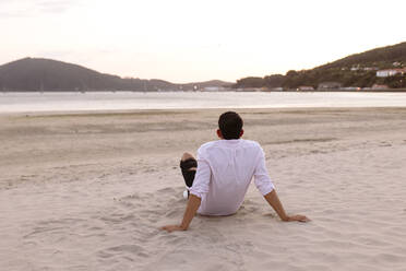 Junger Mann entspannt am Strand bei Sonnenuntergang - EGHF00550