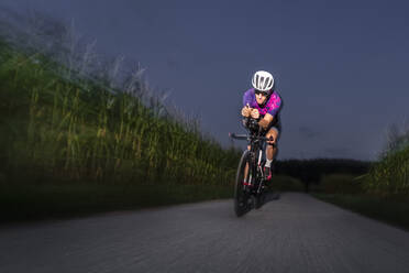 Sportler fährt Rennrad auf der Straße in der Abenddämmerung - STSF03493