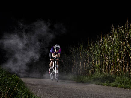 Sportler fährt mit dem Fahrrad auf der Straße bei Nacht - STSF03497