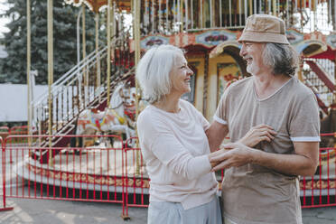 Happy woman enjoying with man in front of carousel - YTF00024