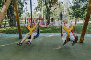 Happy couple having fun swinging in park - YTF00043