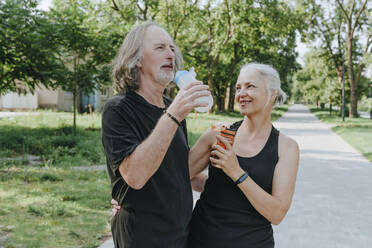 Ältere Frau mit älterem Mann trinkt Wasser im Park - YTF00053