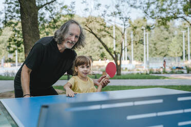 Glücklicher Großvater und Enkelin spielen Tischtennis im Park - YTF00057