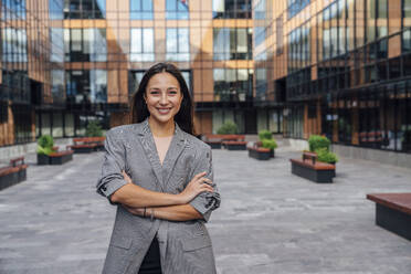 Happy confident businesswoman standing with arms crossed in front of office building - VPIF07138