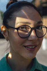Lächelnde Geschäftsfrau mit Sonnenlicht im Gesicht und Brille - VPIF07181
