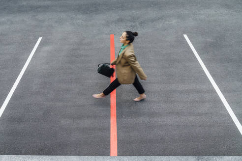 Businesswoman walking over red line at parking lot - VPIF07202