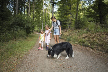 Woman with daughters and pet dog on footpath in forest - DWF00601