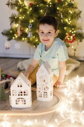 Lächelnder süßer Junge spielt mit Weihnachtsdekoration zu Hause - ONAF00110