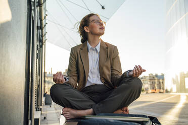 Geschäftsfrau im Schneidersitz meditierend vor einem Bürogebäude - VPIF07253