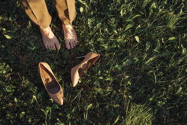 Businesswoman standing by brown stilettos on grass in park - VPIF07288