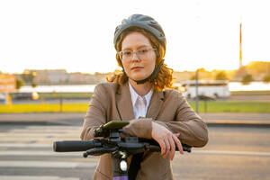 Geschäftsfrau mit Brille, die sich auf einen Motorroller stützt - VPIF07292