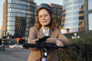 Schöne Geschäftsfrau mit Brille, die sich auf einen Motorroller stützt - VPIF07293