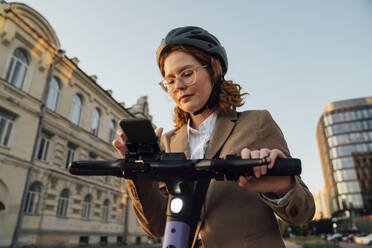 Geschäftsfrau mit Helm und Mobiltelefon in der Stadt - VPIF07296