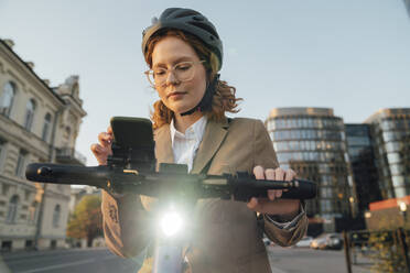 Junge Geschäftsfrau mit Brille benutzt ein Smartphone in der Stadt - VPIF07297