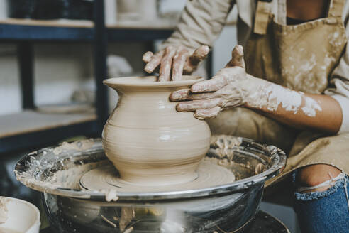 Hands of craftswoman molding pot shape on pottery wheel - YTF00073