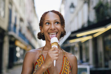 Glückliche junge Frau leckt Eiscreme - DCRF01403