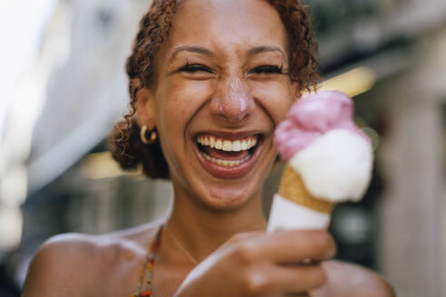 Fröhliche junge Frau, die mit einem Eis in der Hand Spaß hat - DCRF01405