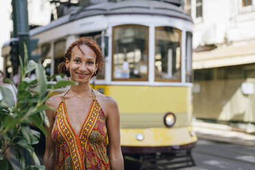 Lächelnde junge Frau vor einer Seilbahn stehend - DCRF01412