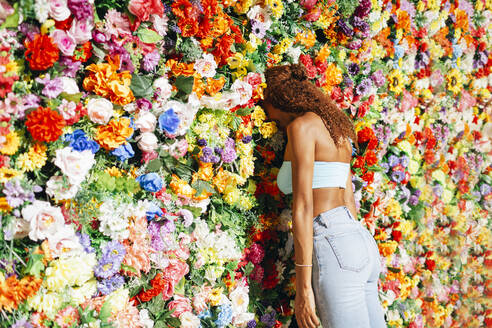 Young curly hair woman leaning head on flower wall - DCRF01445