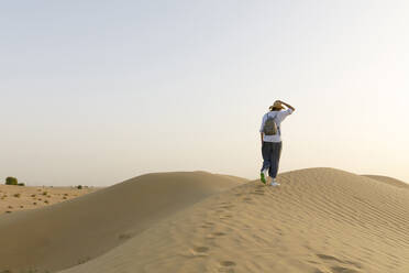 Frau mit Rucksack läuft auf Sanddünen in der Wüste - TYF00418