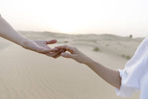 Paar hält Hände in der Wüste bei Sonnenuntergang - TYF00421