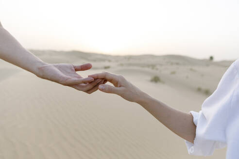 Couple holding hands in desert at sunset - TYF00421