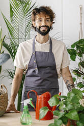 Lächelnder Mann vor einer Pflanze auf einem Tisch in einem Geschäft - XLGF03086