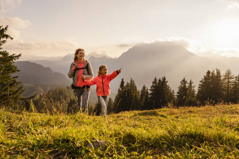 Smiling woman holding daughter's hand hiking on mountain - DIGF18777