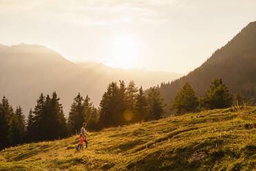 Mann mit Tochter beim Wandern auf einem Berg bei Sonnenuntergang - DIGF18793