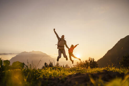 Happy man with daughter jumping on top of mountain - DIGF18812