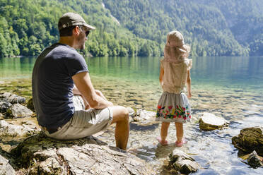 Mann sieht Tochter im See stehend an - DIGF18829