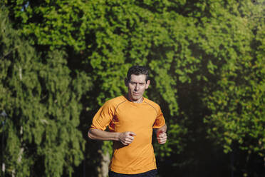 Mature sportsman running on sunny day - ASGF02893