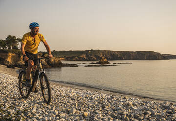 Glücklicher Mann fährt Fahrrad am Strand - UUF27224