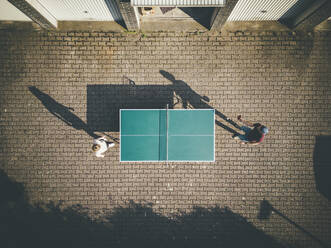 Mann mit Tochter spielt Tischtennis im Hinterhof - JOSEF13239