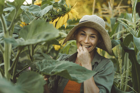 Lächelnde reife Frau isst Sonnenblumenkerne im Garten - IEF00093